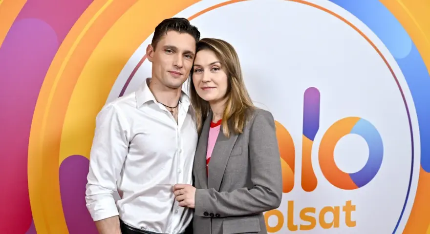 Małgorzata Patryn Gurłacz z partnerem pozują na tle kolorowego logo.