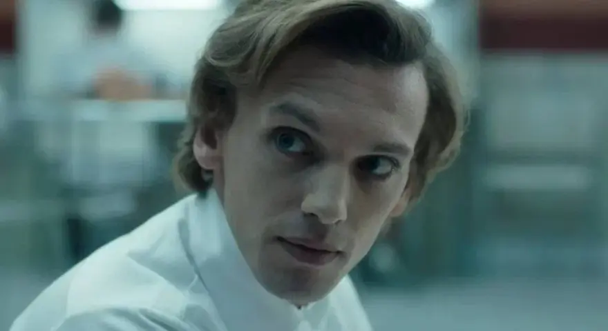 Henry Creel, znany jako Vecna z 001 stranger things, w białej koszuli, patrzy z uwagą.