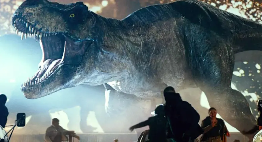 Gigantyczny Tyranozaur Rex z Jurassic World 3 z otwartą paszczą ściga ludzi wśród samochodów.