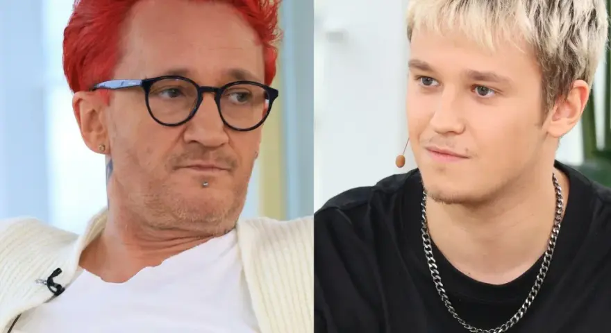 Xavier Michał Wiśniewski z charakterystycznymi rudymi włosami i okularami obok młodszego mężczyzny z blond fryzurą.