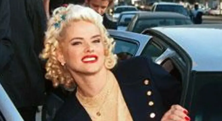 Anna Nicole Smith, z burzą blond loków i czerwoną szminką, wysiada z samochodu.