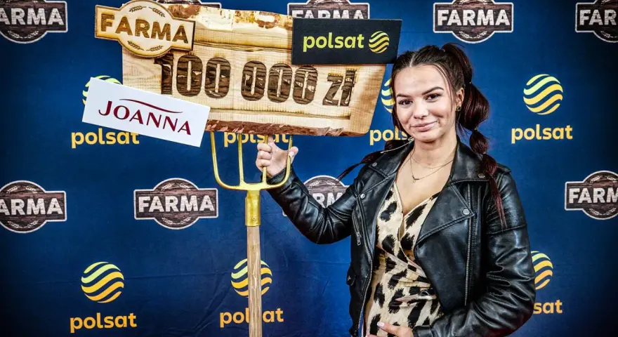 Joanna z "Farmy" trzyma widły i tablicę z napisem "100 000 zł".
