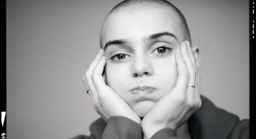 Sinead O'Connor z dłońmi opartymi o policzki, zamyślona.