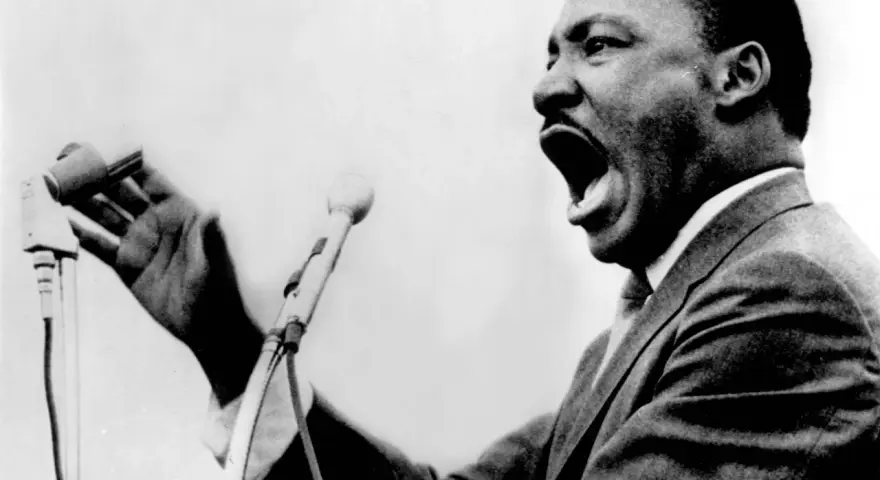 Martin Luther King przemawia z pasją do mikrofonu, jego głos niesie nadzieję i wolność.