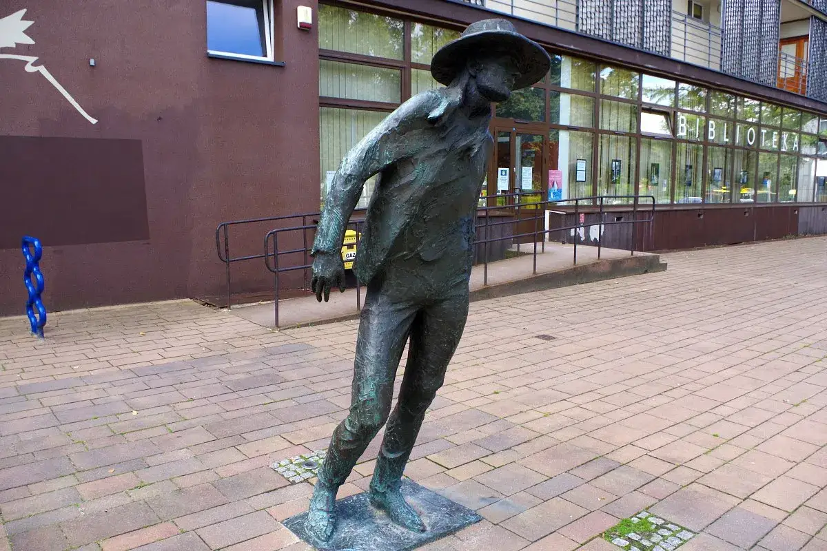 Brązowy posąg mężczyzny w kapeluszu, skazany na bluesa, stoi przed biblioteką.