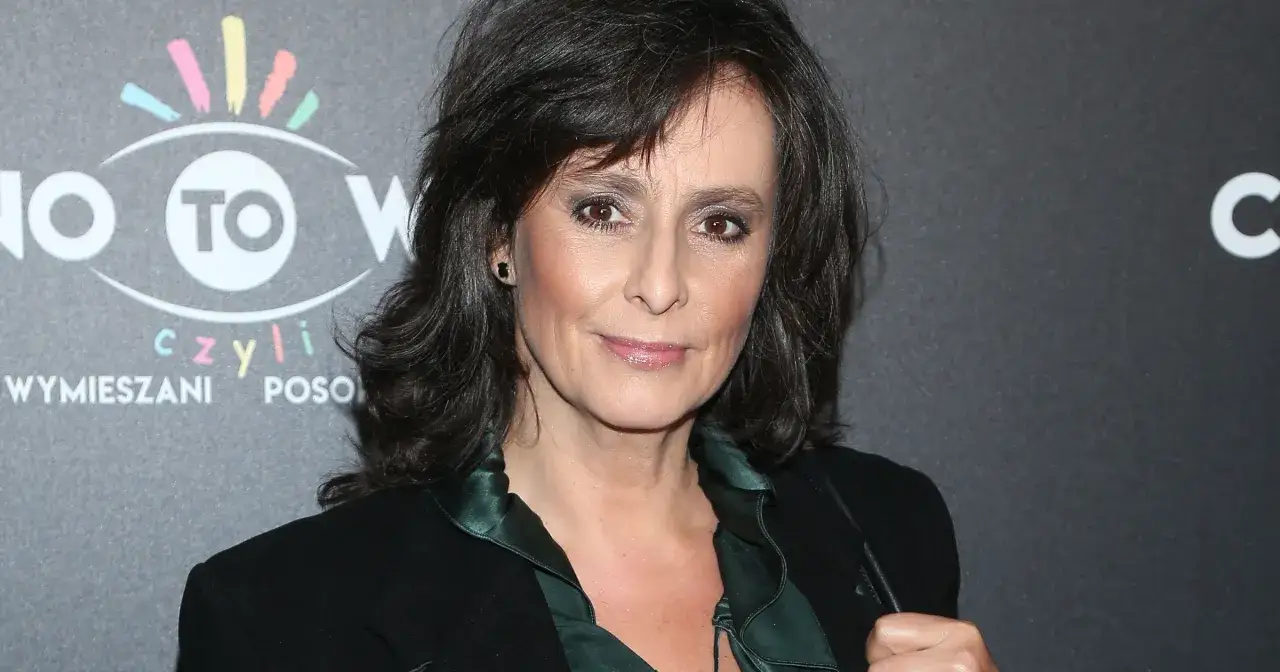 Anna Maria Korcz z uśmiechem na twarzy, w eleganckiej stylizacji, pozuje na tle wydarzenia