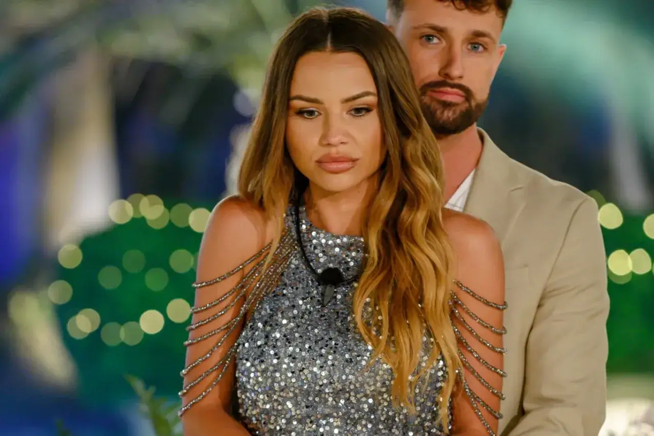 Love Island 7 uczestnicy: zjawiskowa blondynka w błyszczącej sukience i jej partner w beżowym garniturze.