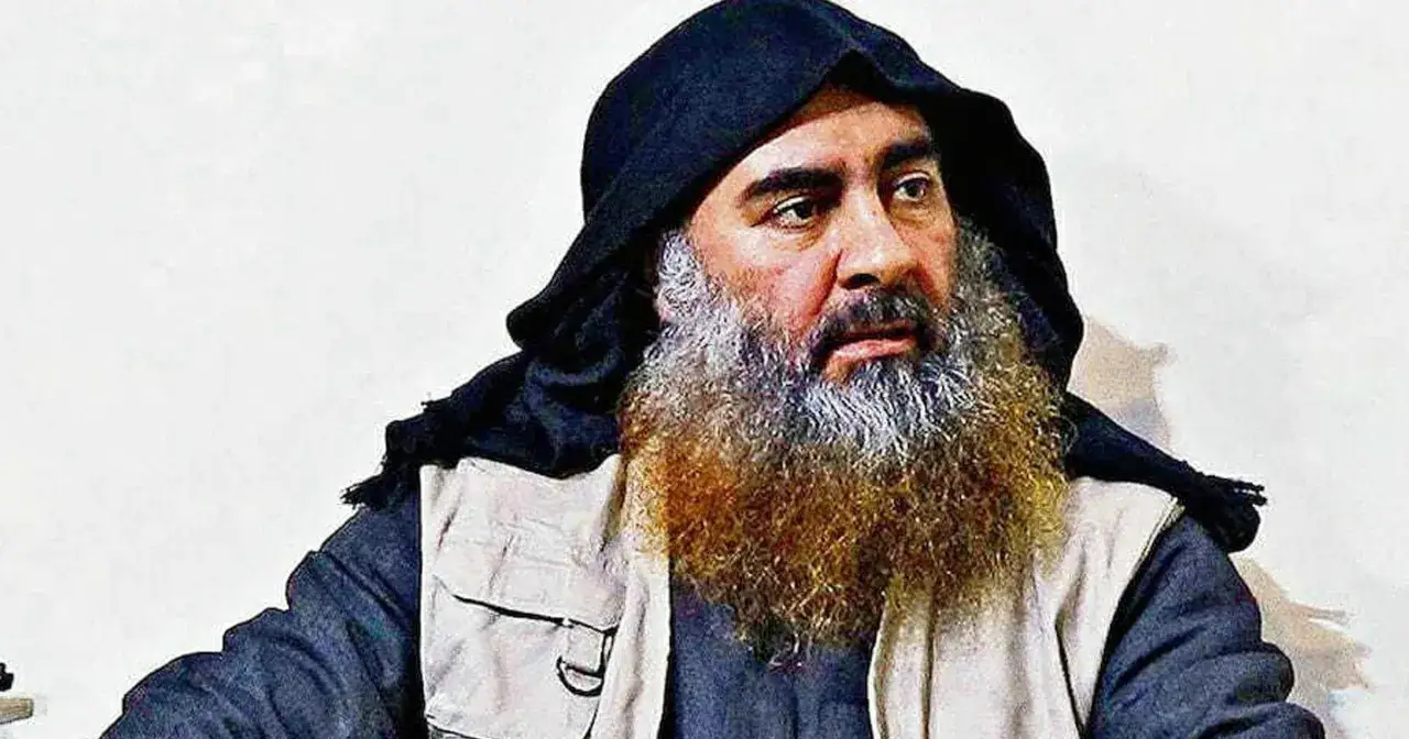 Mężczyzna z długą, siwiejącą brodą i czarnym nakryciem głowy, przypominający Abu Bakra al-Baghdadiego, w jasnej kamizelce.
