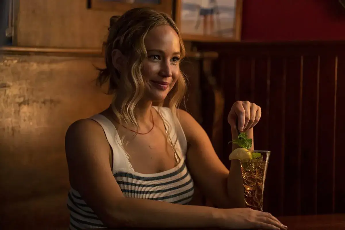 Uśmiechnięta kobieta z blond włosami, w białej bluzce w paski, dodaje miętę do drinka. No hard feelings, po prostu relaks.