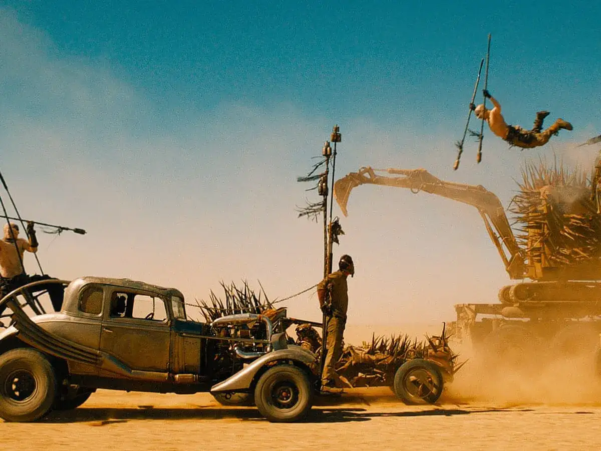 Mad Max na drodze gniewu: szalona akcja na pustyni. Człowiek skacze z koparki na pojazd, walcząc o przetrwanie.