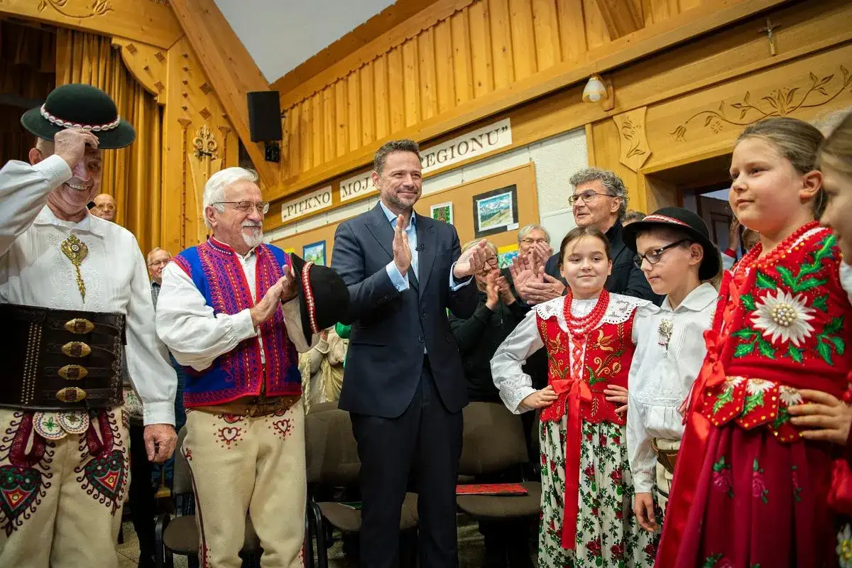 Rafał Trzaskowski, ile lat ma, wita góralską społeczność. Ludzie w tradycyjnych strojach klaszczą.