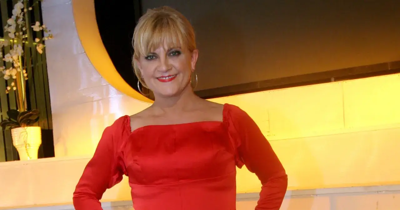 Marzena Kipiel w czerwonej sukni, uśmiechnięta, prezentuje swoją sztukę.